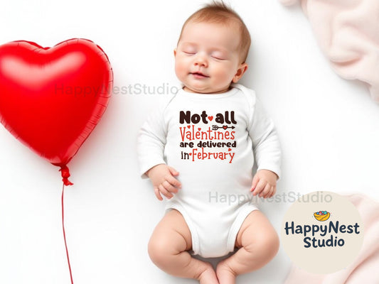 A peacefully sleeping baby wearing a white long-sleeve cotton onesie with envelope-style shoulders and snap closures at the bottom for easy diaper changes. The onesie features a playful Valentine's-themed design with the phrase "Not all Valentines are delivered in February" printed in bold brown and red lettering, accented with heart and arrow graphics. The soft, breathable fabric ensures comfort for delicate baby skin.