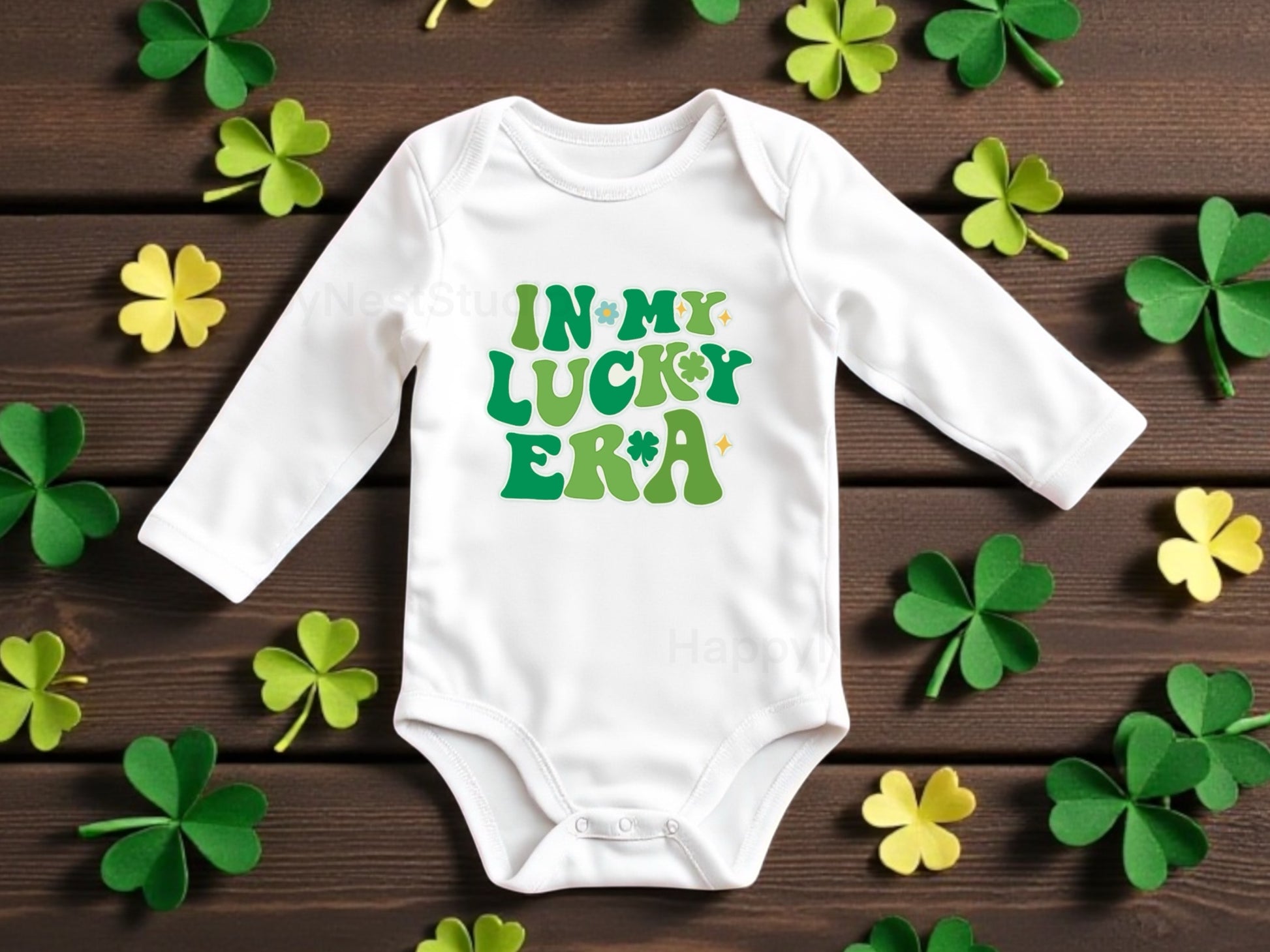 White long-sleeve baby onesie featuring a unique, shop-owner–designed sublimated printable-vinyl graphic that reads ‘In My Lucky Era’ in multiple shades of Irish green lettering. This handmade Saint Patrick’s Day baby bodysuit is perfect for Irish-themed celebrations, newborn baby gifts, or a cute everyday outfit for infant boys or girls. Ideal for parents searching for shamrock-inspired newborn clothing, green baby onesies, sublimation baby outfits, and funny, cute Irish baby gift ideas.